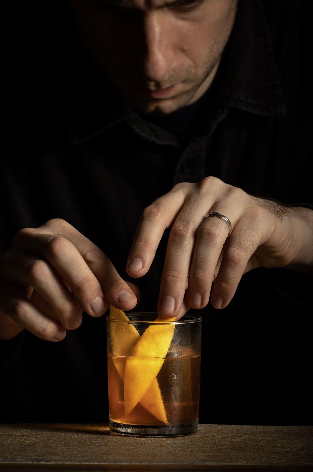 a man decorating a glass of soju with lemons